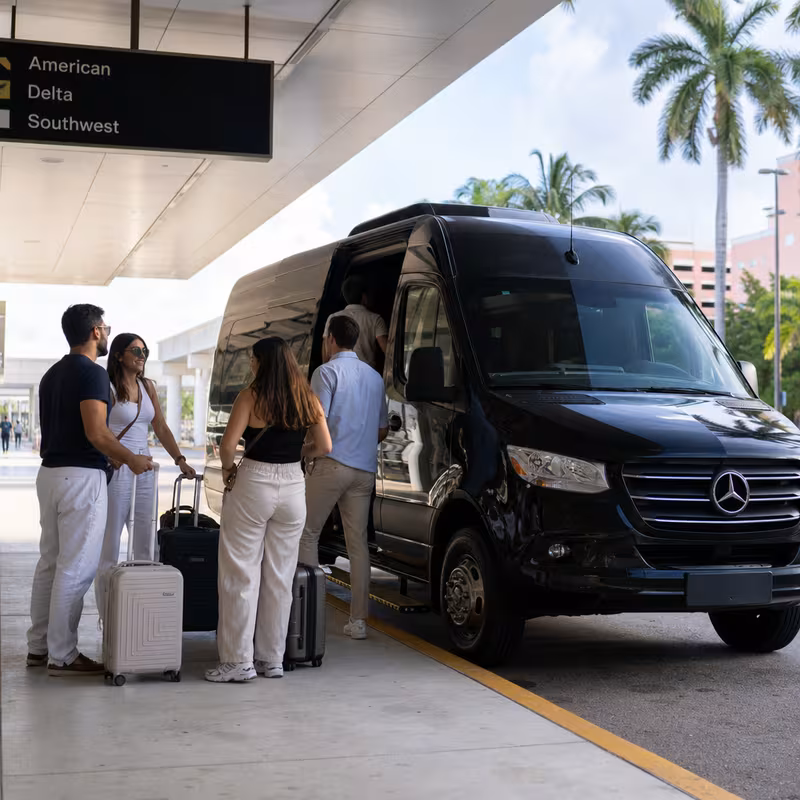 Group boarding a white charter bus for Airport Transportation transportation in Coral Gables